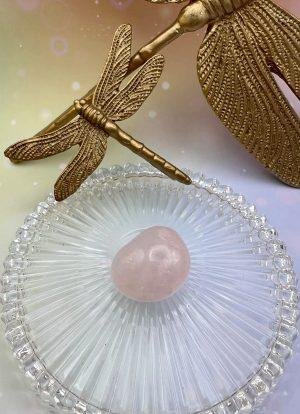 Pierre roulée en quartz rose sous une libellule dorée – symbole d’amour, de lumière et d’harmonie du cœur