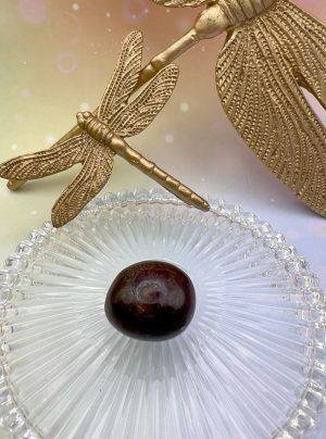 Pierre roulée en grenat rouge entourée de libellules dorées – symbole d’énergie, de passion et d’enracinement