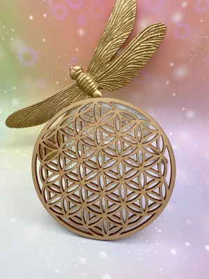 Fleur de vie en bois posée devant une libellule dorée, accessoire de purification énergétique.