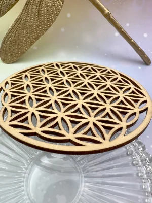 Fleur de vie en bois vue de dessus, posée sur un bol en verre transparent.